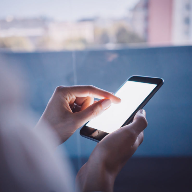 Girl touching a screen of her smarthone on the blurred background. Horizontal
